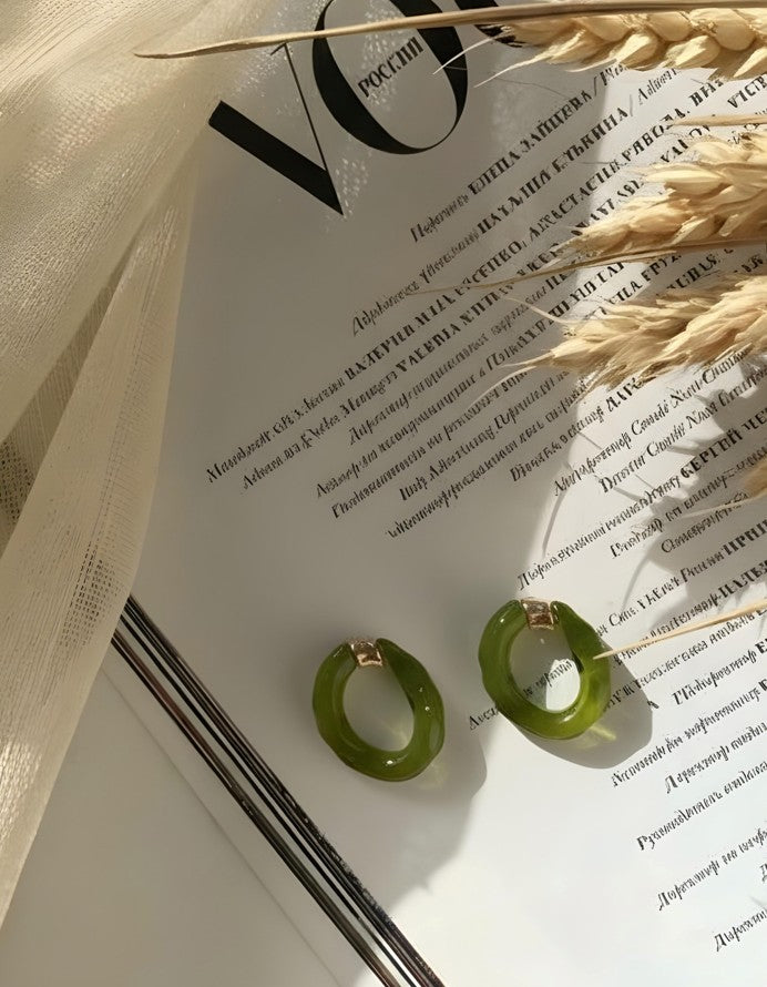 Glossy green Lucent Loop Earrings styled on a magazine page