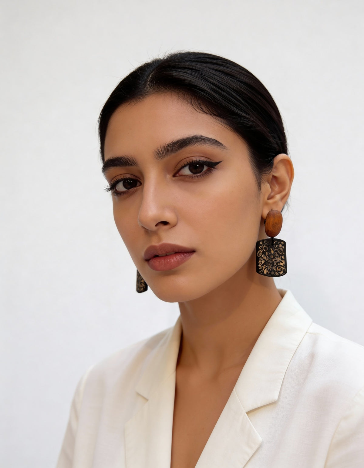Model wearing black engraved floral Noir Bloom Earrings with natural wood oval studs